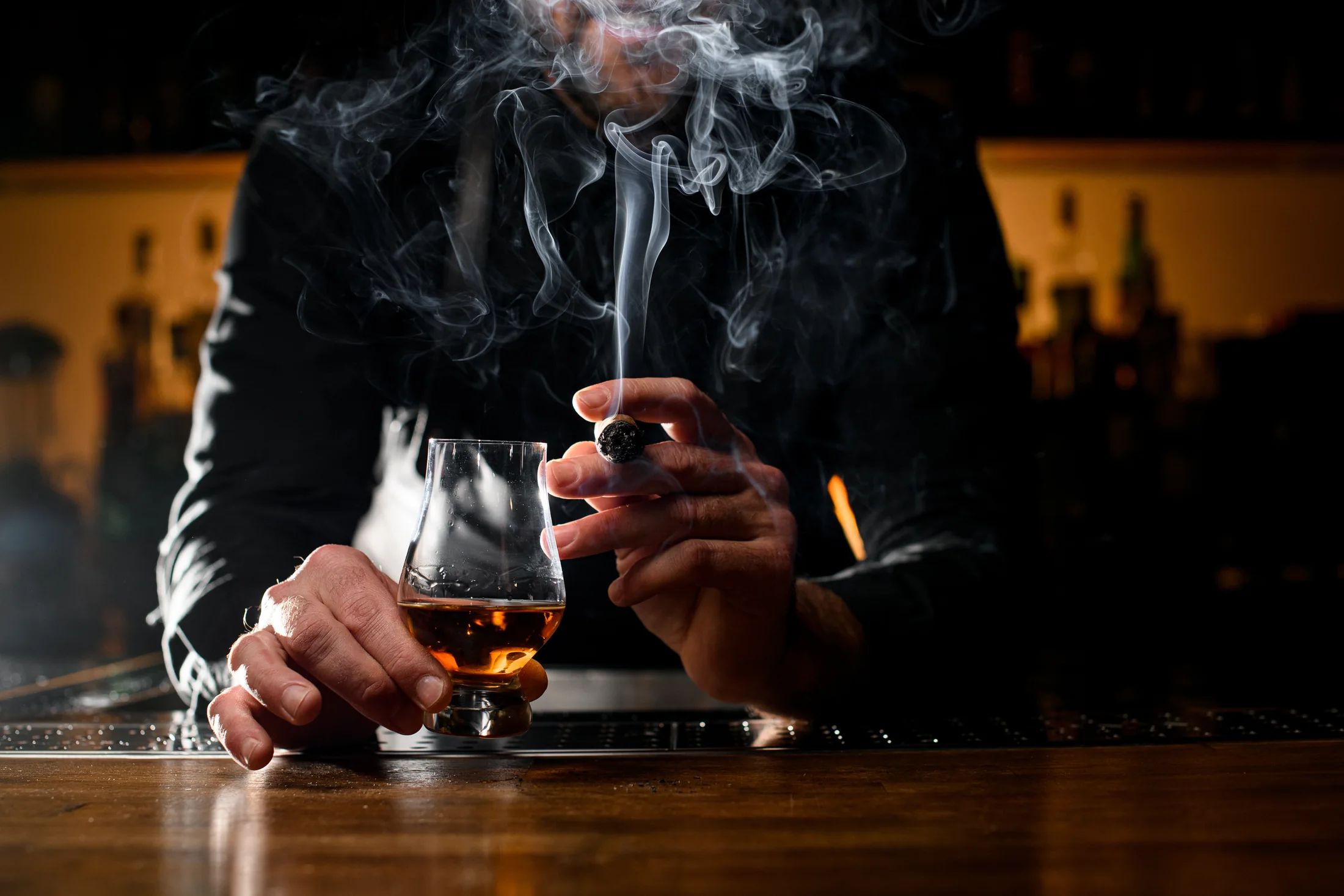 A premium cigar beside a glass of whiskey